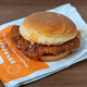 Burger King spicy chicken sandwich sitting on wrapper on wooden surface
